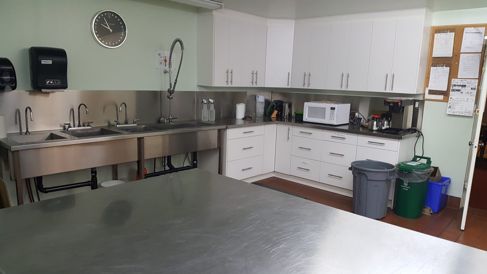 The kitchen's triple stainless sink, prep counters and white cupboards.
